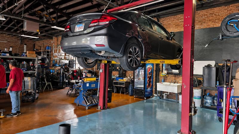 A vehicle raised on a red lift inside the ERMAK Tires service bay.